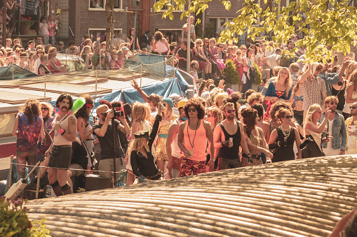 A vintage color tone picture of amsterdam gay parade in a canal on a sunny day with people having fun dancing on a boat stock photo