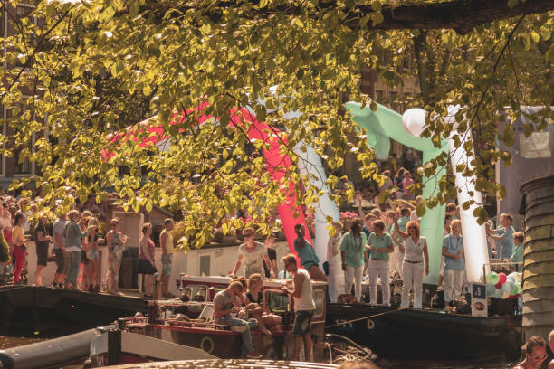 A vintage color tone picture of amsterdam gay parade in a canal on a sunny day with people having fun dancing on a boat stock photo