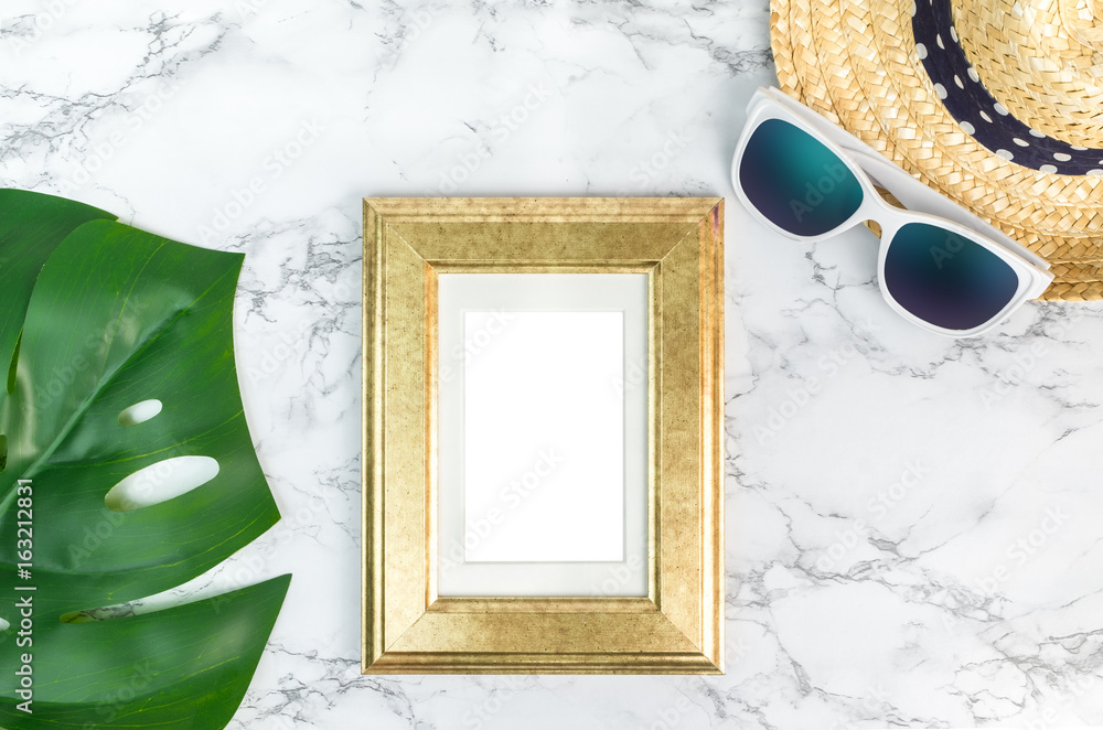 Blank vintage golden color picture frame on green monstera leaf with sunglasses and straw hat on white marble table top viewmock up for adding your photo in copy spacesummer vacation photo